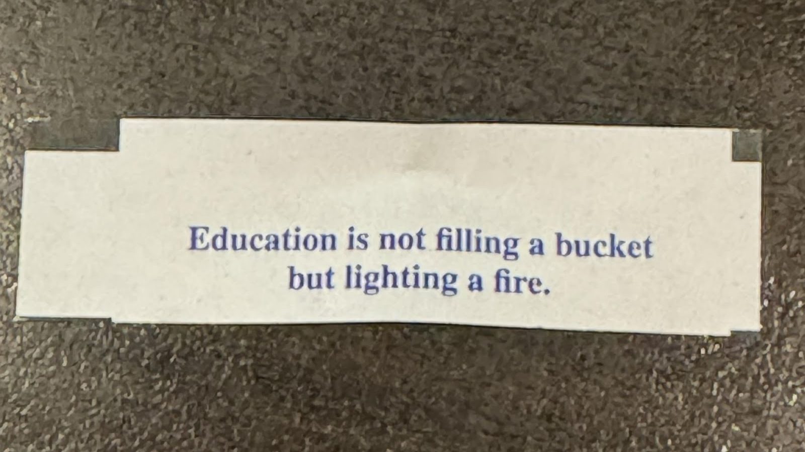 A picture of a fortune from fortune cookie that states Education is not filling a bucket but lighting a fire.
